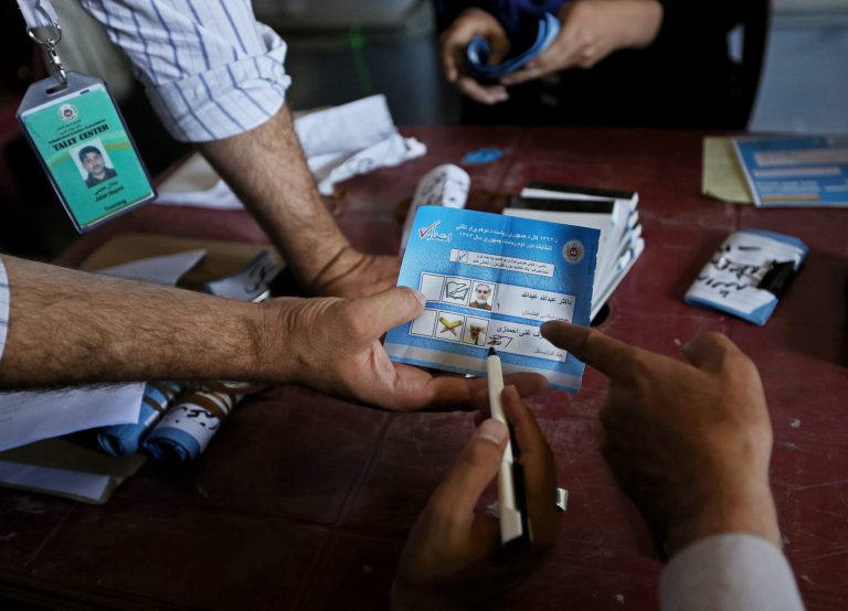 FILE - In this Friday, July 18, 2014 file photo, Afghan election commission workers look at a ballot for an audit of the presidential run-off votes at a election commission office in Kabul, Afghanistan. Despite lingering disputes, Afghan electoral officials said Thursday, July 31, 2014 that they will resume an audit of the presidential election this weekend after the presidential candidates sparred over how to disqualify ballots amid allegations of massive fraud. (AP Photo/Rahmat Gul, File)