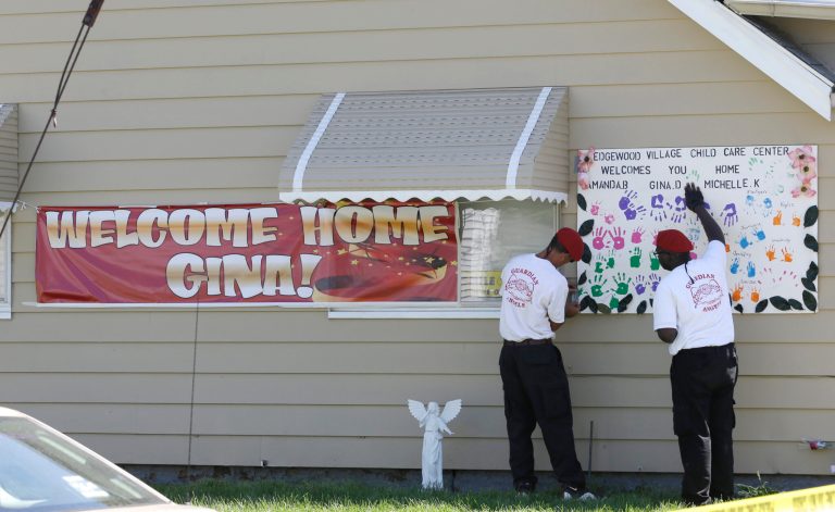 Two Gaurdian Angels hang a poster at the home of Gina DeJesus Thursday, May 9, 2013, in Cleveland. Ariel Castro, the man accused of raping and kidnapping DeJesus and two other women, who were missing for about a decade before being found alive at his home, was ordered held Thursday on $8 million bail. (AP Photo/Tony Dejak)