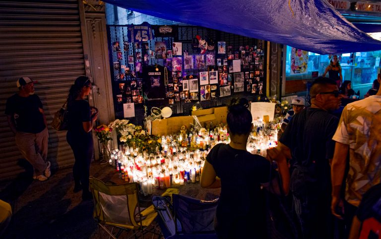 Candles are lit at a memorial in New York, Monday, Aug. 18, 2014, in memory of two men who died Sunday after a gunman got out of his car and opened fire. New York City Mayor Bill de Blasio says the city's police force is zeroing in on the sites of 23 shootings over the weekend. (AP Photo/Craig Ruttle)
