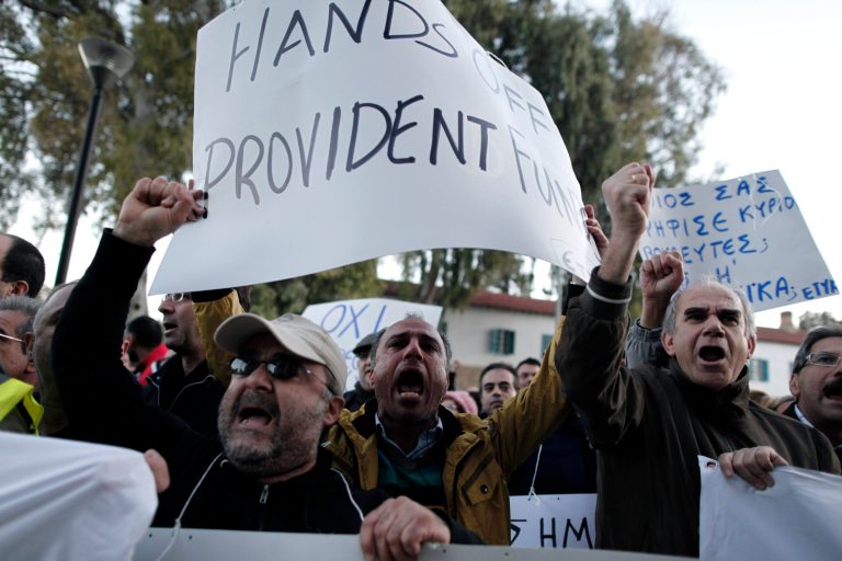 Bank employees protest outside the ministry of finance on Saturday, March 23, 2013. Thousands of bank employees took part in a protest that ended outside the Cypriot parliament. Politicians in Cyprus were racing Saturday to complete an alternative plan raising funds necessary for the country to qualify for an international bailout, with a potential bankruptcy just three days away. Banner at right reads: 
