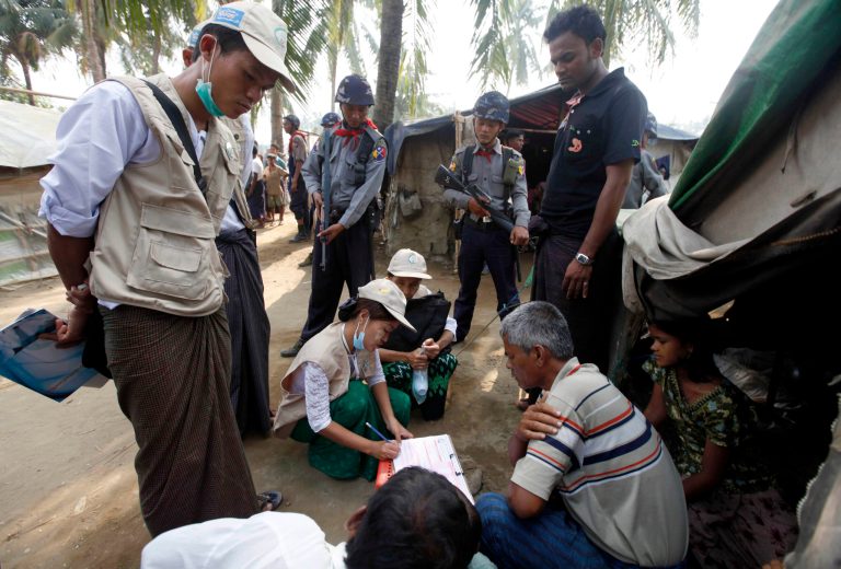 Policemen stand guard as census enumerators, center, asks questions to collect information from a family at Thae Chaung village in Sittwe, Rakhine State, western Myanmar, Tuesday, April 1, 2014. Enumerators fanned out across Myanmar on Sunday for a census that has been widely criticized for stoking religious and ethnic tensions, after the government denied members of a long-persecuted Muslim minority the right to identify themselves as "Rohingya." (AP Photo/Khin Maung Win)