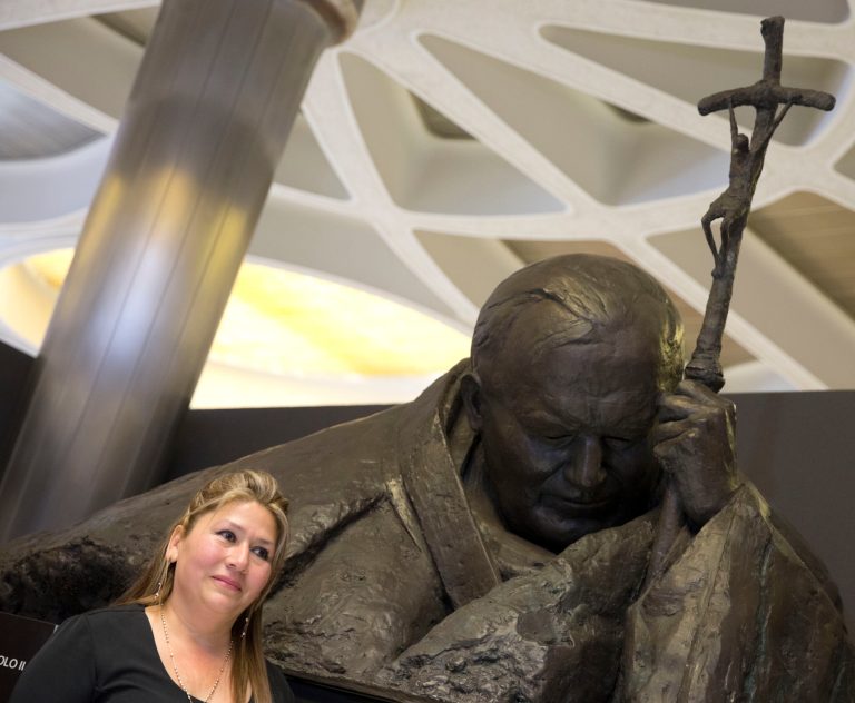 Floribeth Mora, a  Costa Rican woman whose inoperable brain aneurysm purportedly disappeared after she prayed to John Paul II, walks past a statue of him made by Polish artist Anna Gulak as she leaves after a press conference at the Vatican, Thursday, April 24, 2014. John Paul II will be made saint together with late Pope John XXIII during a solemn ceremony at the Vatican Sunday.  (AP Photo/Alessandra Tarantino)