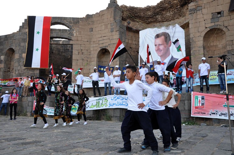 In this Saturday, May 31, 2014, photo released by the Syrian official news agency SANA, supporters of Syrian President Bashar Assad hold his portraits and wave Syrian flags during a demonstration in support of his candidacy for presidential election in Sweida town, southern Syria. The country holds its first multi-candidate presidential election in nearly half a century on Tuesday, June 3, but voting will occur only in government-held territory. Hundreds of thousands of people live in areas that are either contested, held by rebels or blockaded by pro-government forces. (AP Photo/SANA)