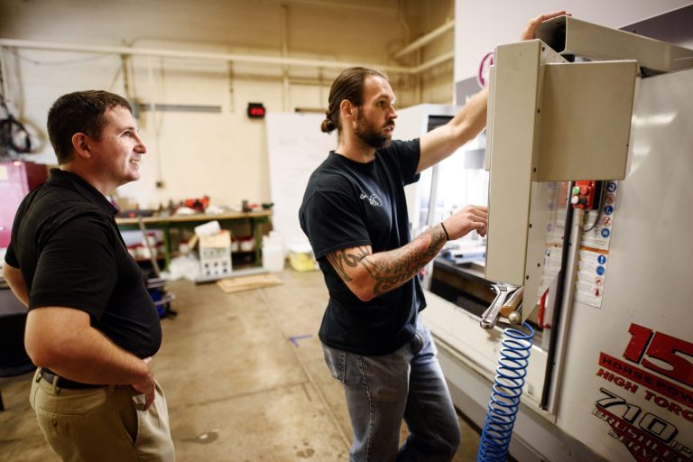 Brett Conner, Ph.D., associate professor in the Department of Mechanical and Industrial Engineering in Youngstown State University, left, watches graduate student Mike Juhasz, 32, work on a 3D printer (a hybrid additive manufacturing machiner system) on Sept. 5 in Youngstown, Ohio. (Justin Merriman for The Washington Examiner)