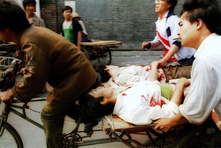 FILE - In this June 4, 1989 file photo, a rickshaw driver peddles wounded people, with the help of bystanders, to a nearby hospital in Beijing after they were injured during clashes with Chinese soldiers in Tiananmen Square. The crackdown ended a period of relative political openness, led to the downfall of Communist Party leader Zhao Ziyang and plunged Beijing into diplomatic isolation that lasted until the late 1990s. (AP Photo/Liu Heung Shing, File)