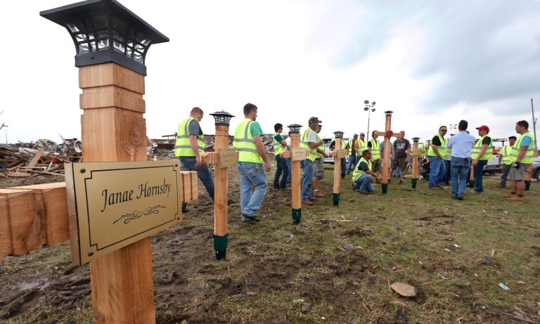 Maintenance workers from the Moore Public Schools erect crosses at the Plaza Towers elementary school that they built in memory of the seven children who died during the Moore tornado, Friday, May 24, 2013 in Moore, Okla. One large cross and seven smaller crosses with the names of the victims are in memory of the seven students who died in the Moore tornado.(AP Photo/Sue Ogrocki)