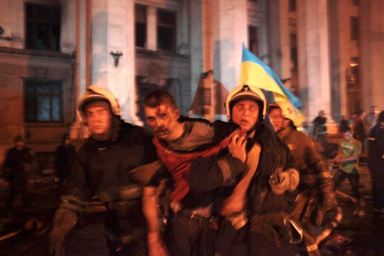 Firefighters evacuate an injured man outside the burnt trade union building where more than 30 people died trying to escape during clashes in Odessa, Ukraine, on Friday, May 2, 2014. Odessa had been largely tranquil since the February toppling of President Viktor Yanukovych, who fled to Russia. But clashes erupted Friday between pro-Russians and government supporters in the key port on the Black Sea coast, located 550 kilometers (330 miles) from the turmoil in the east. (AP Photo/Sergei Poliakov)