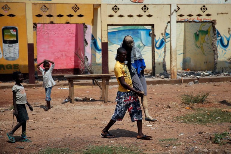 A Christian man carries a charred mannequin wearing a Muslim veil in front of looted Muslim stores, past a convoy of over 100 vehicles of Muslims fleeing Bangui, Central African Republic, Friday Feb. 14, 2014. A convoy of thousands of Muslims heading to Chad had to turn around as MISCA troops, the African force deployed in the Central African Republic, deemed the road out was not secure. (AP Photo/Jerome Delay)