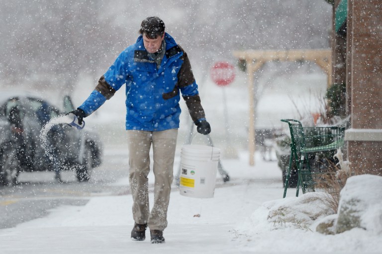 REI Assistant Store Manager Noel Seeburg salts the sidewalk after shoveling in front of the store located in the Cranbrook Village Shopping Center in Ann Arbor, Mich. on Wednesday, Dec. 26, 2012. 