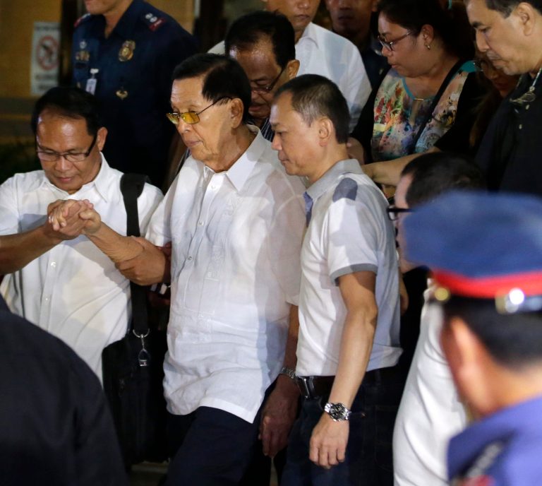 Former Senate President Juan Ponce Enrile, second left, is helped to a waiting ambulance after undergoing processing at the Philippine National Police upon his surrender on corruption charges Friday, July 4, 2014 at Camp Crame at suburban Quezon city, northeast of Manila, Philippines. Enrile, 90, surrendered Friday to face a charge of large-scale corruption, the most prominent of three top politicians to fall in a government anti-graft crackdown in recent weeks. (AP Photo/Bullit Marquez)