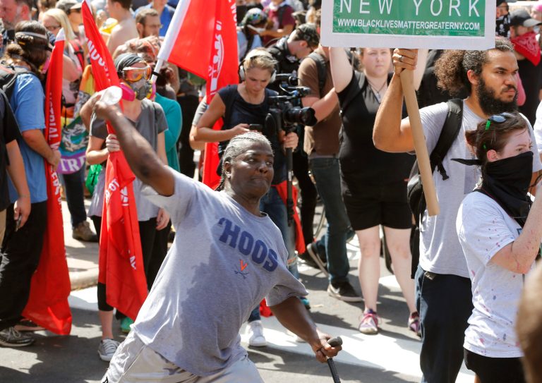 A counter demonstrator throws a water bottle at an white nationalist demonstrator at the entrance to Lee Park in Charlottesville, Va., Saturday, Aug. 12, 2017. (AP Photo/Steve Helber)