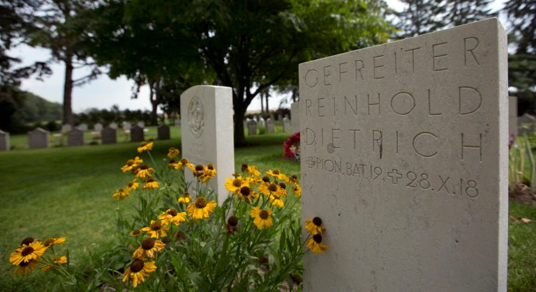 In this Saturday, July 26, 2014 file photo, World War I German Corporal Reinhold Dietrich, right, and British Captain Kenneth James Roy are buried side by side at the Saint Symphorien Cemetery near Mons, Belgium. Separated by only a small patch of yellow daisies at the Saint-Symphorien military cemetery lie two former enemies: British Captain Kenneth James Roy and German Gefreiter (Corporal) Reinhold Dietrich. Also between the two are some 9 million dead soldiers over four years. (AP Photo/Virginia Mayo, File)