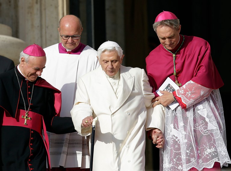 Pope Emeritus Benedict XVI, center, is helped to walk down the steps by Bishops Vincenzo Paglia, left, and Georg Gaenswein prior to the start of a meeting of Pope Francis with elderly in St. Peter's Square at the Vatican, Sunday, Sept. 28, 2014. (AP Photo/Gregorio Borgia)