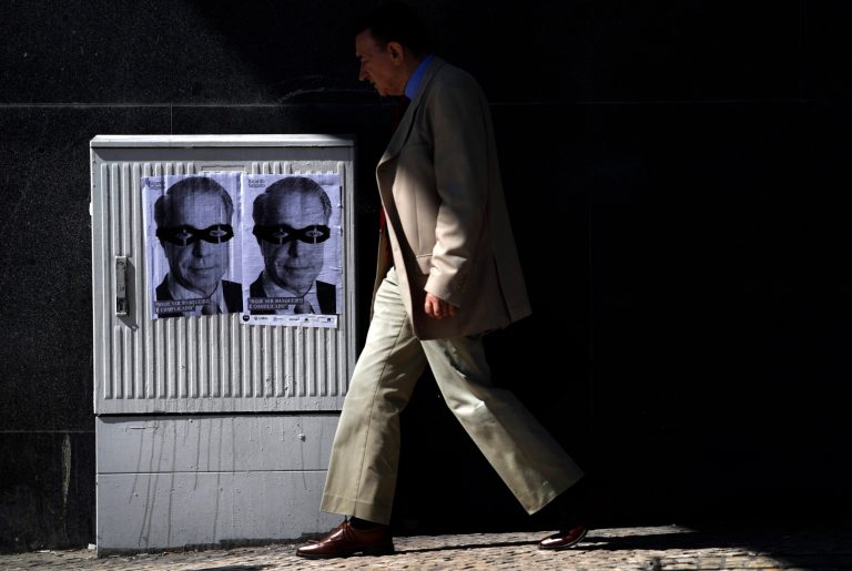 A man walks past posters with the face of Portuguese bank Banco Espirito Santo's former chief executive Ricardo Salgado depicting him wearing a mask and reading in Portuguese: 