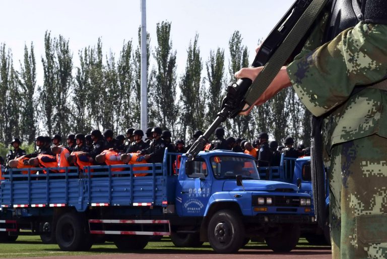 In this photo taken on Tuesday, May 27, 2014, Chinese residents and officials attend a public sentencing of 55 people dressed in orange vests in a stadium in Yili, in northern Xinjiang province of northwest China. In the stadium filled with 7,000 people, a Chinese court announced guilty verdicts for 55 people on charges of terrorism, separatism and murder as the government tries to display its determination to combat unrest in the troubled northwest region. (AP Photo) CHINA OUT