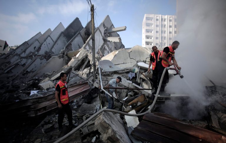 FILE - In this Tuesday, Aug. 26, 2014 file photo, Palestinian firefighters extinguish a fire in the rubble of the destroyed 15-story Basha Tower, following early morning Israeli airstrikes in Gaza City.  Shelter Cluster, chaired by the Norwegian Refugee Council with the participation of the U.N. refugee agency and the Red Cross, an international organization involved in assessing post-conflict reconstruction, said in a report issued late Friday, Aug 29, 2014, it will take 20 years under current levels of restrictions to rebuild the Gaza Strip's battered and neglected housing stock following the war between Hamas and Israel. (AP Photo/Khalil Hamra, File)