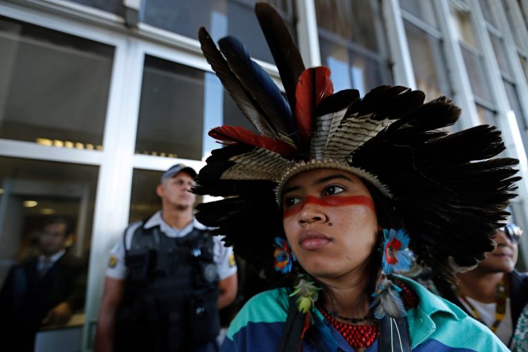 A Gaviao Indian woman stands with other protesters, blocking a Ministry of Justice employee entrance, during a protest to demand the demarcation of indigenous lands in Brasilia, Brazil, Thursday, May 29, 2014. The indigenous protesters are demanding to meet with Justice Minister Eduardo Cardozo to discuss the reservation-reduction legislation. (AP Photo/Eraldo Peres)
