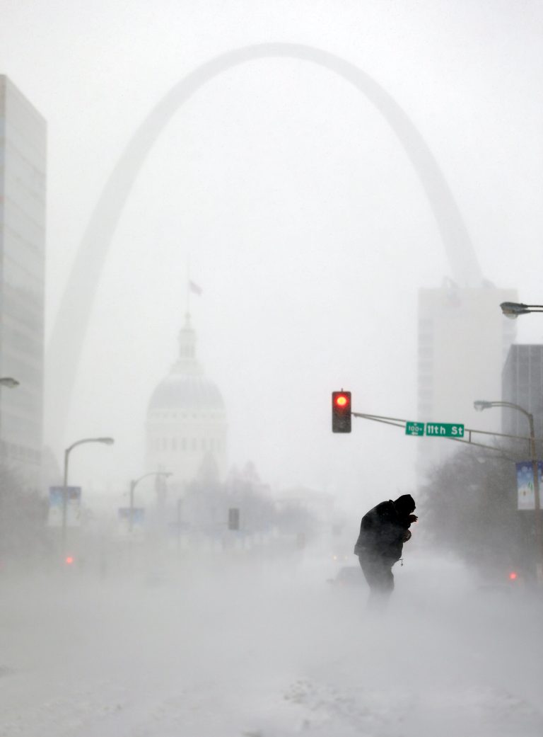 FILE - In this Sunday, Jan. 5, 2014, file photo, a person struggles to cross a street in blowing and falling snow as the Gateway Arch appears in the distance, in St. Louis. The deep freeze that gripped much of the nation this week wasn't unprecedented, but with global warming we're getting far fewer bitter cold spells, and many of us have forgotten how frigid winter used to be. (AP Photo/Jeff Roberson, File)