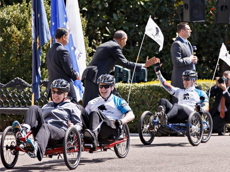 President Barack Obama, accompanied by Veterans Affairs Secretary Eric Shinseki, left, welcome the Wounded Warrior Projectâs Soldier Ride as they circle the South Lawn of the White House in Washington, Thursday, April 17, 2014. The cyclists were in specially built bikes that could accommodate amputations or other injuries. (AP Photo/J. Scott Applewhite)