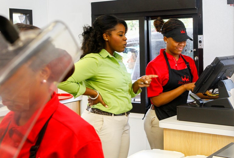 In this July 31, 2014 photo, Quamisha Nelson, owner and operator of the Smoothie King in Jacksonville, N.C., center, works alongside Latasia White, 15, as she rings up a customer's order at the drive-thru. The government reports on state unemployment rates for July on Monday, Aug. 18, 2014. (AP Photo/The Jacksonville Daily News, John Sudbrink)