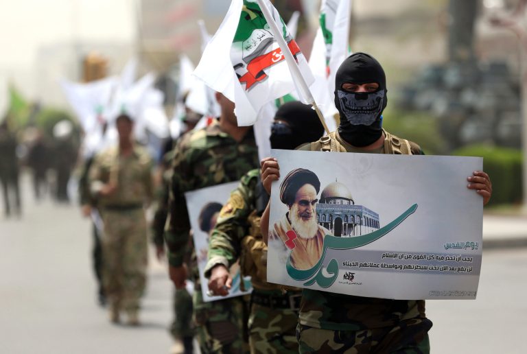 Supporters of Iraqi Hezbollah brigades march in military uniforms with a portrait of Iran's supreme late Iranian leader Ayatollah Khomeini in Baghdad, Iraq, during a parade marking Quds Day. (AP/Hadi Mizban)