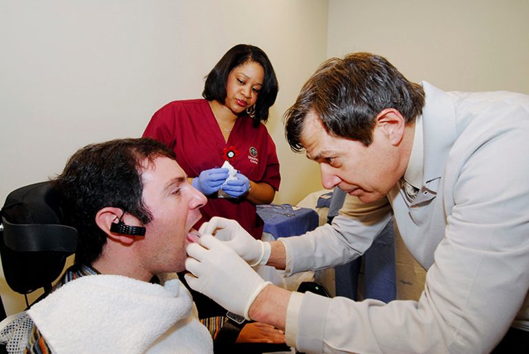 This undated handout photo provided by the Shepherd Center shows Jason DiSanto, left, receiving a tongue piercing at Georgia Tech in Atlanta.  An experimental device is letting paralyzed people drive wheelchairs simply by flicking their tongue in the right direction.  The Tongue Drive System was developed at Georgia Tech and tested at Shepherd Center in Atlanta.  (AP Photo/Georgia Tech, Gary Meek)
