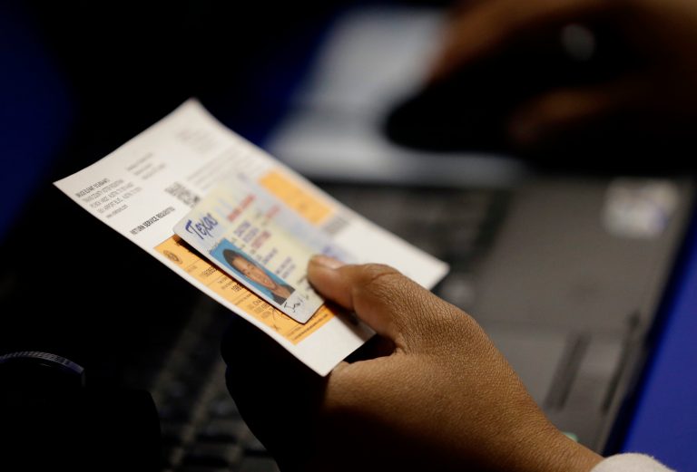 In this Feb. 26, 2014 file photo, an election official checks a voter's photo identification at an early voting polling site in Austin, Texas. (AP Photo/Eric Gay, File)