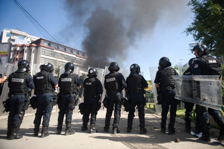 Kosovo police in riot gear deploy to disperse a crowd of hundreds of stone-throwing protestors demanding removal of a blockade of flower pots on a bridge linking ethnic Albanians and Serbs in the ethnically divided town of Mitrovica on Sunday, June 22, 2014. Police said at least seven officers were injured as some 5 cars set ablaze as ethnic Albanian protested ethnic Serbs barricading the Serb run north from the ethnic Albanian south. (AP Photo/Visar Kryeziu)