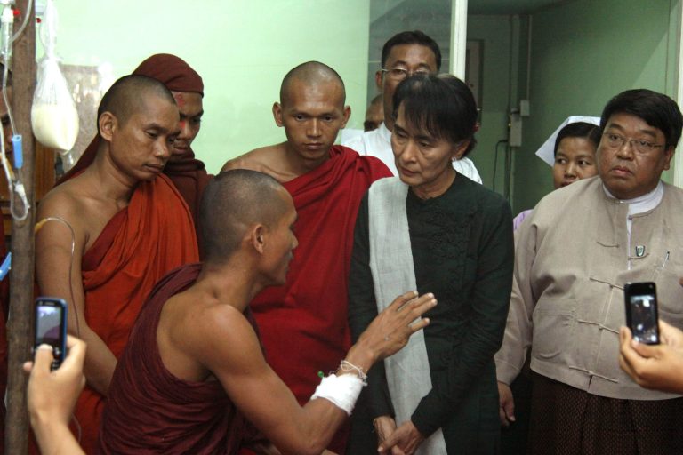   FILE - In this Thursday, Nov 29, 2012 file photo, opposition leader Aung San Suu Kyi, second right, listens to a Buddhist monk who suffered from burn injuries when security forces cracked down protesters camping at a military-backed copper mine, during her visit to a hospital in Monywa, northwestern Myanmar. For Suu Kyi the democracy activist, the 25-year struggle against Myanmar's former army rulers was a largely black-and-white affair - a clear fight for freedom against one of the world's most oppressive regimes. But Suu Kyi the elected lawmaker is finding it a lot more difficult to pick her battles, and she's a lot more pragmatic when she does. (AP Photo/File)  