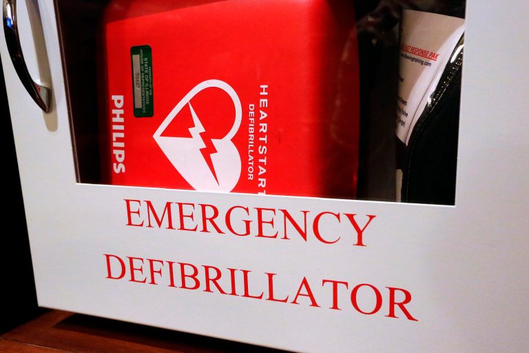 In this Tuesday, July 1, 2014 photo, an emergency defibrillator, used to treat life threatening conditions that affect the rhythm of the heart such as cardiac arrhythmia, hangs on the wall at the Illinois State Capitol Tuesday, July 1, 2014, in Springfield, Ill. A new Illinois law prompted by the death of a high school student during dance practice requires students learn CPR and how to operate Automated External Defibrillators machines used to treat emergency heart problems. (AP Photo/Seth Perlman)