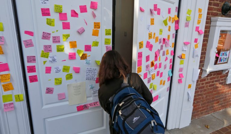 A student walks into Peabody Hall the undergraduate admissions building at the University of Virginia in Charlottesville, Va. The door of the building is littered with notes relating to the recent gang rape allegations. (AP Photo/Steve Helber)
