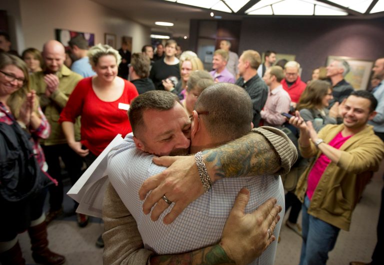 Chris Serrano, left, and Clifton Webb embrace after being married, as people wait in line to get licenses outside of the marriage division of the Salt Lake County Clerk's Office in Salt Lake City in December. (AP/Kim Raff)