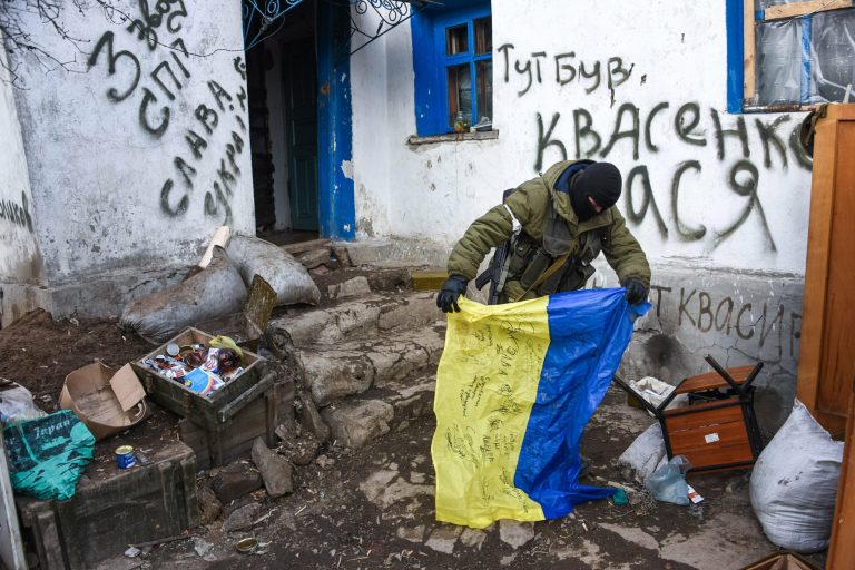 A pro-Russian rebel holds a Ukrainian flag found in a check-point captured by pro-Russian rebels, at the town of Krasniy Partizan, eastern Ukraine. (AP Photo/Mstyslav Chernov)