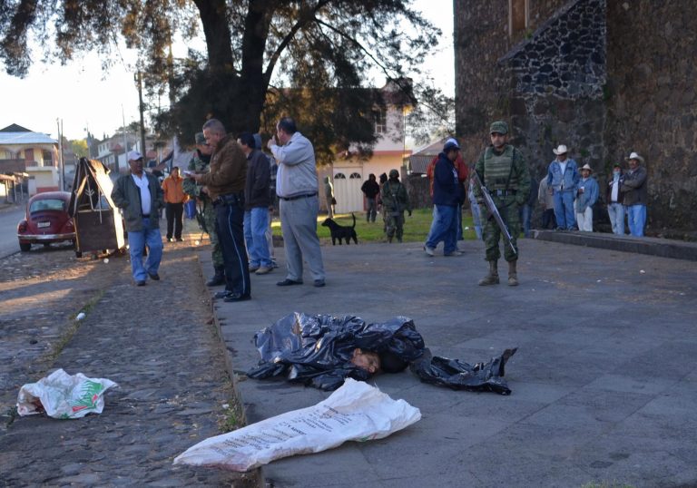 EDS NOTE GRAPHIC CONTENT - Investigators and army soldiers stand near the entrance of a church where four human heads were dumped in the town of Zacan, state of Michoacan, Mexico, Thursday, Feb. 6, 2014. Officials say the remains belong to four men between the ages of 22 and 55 years of age. Mexico's federal government in recent weeks has sent thousands of soldiers and federal police after self-defense groups organized to battle with the Knights Templar drug cartel. (AP Photo/Agencia Esquema)