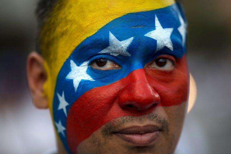 David Aranguren, his face painted with a representation of Venezuela's national flag, poses for a photo during an anti-government demonstration in Caracas, Venezuela, Saturday, Feb. 22, 2014. Supporters and opponents of the government of President Nicolas Maduro are holding competing rallies in the bitterly divided country.
