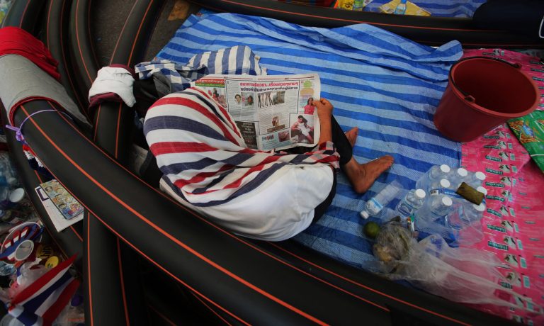 An anti-government protester reads a newspaper during a gathering Thursday, May 22, 2014 in Bangkok, Thailand. Journalists and rights groups have criticized the army for primarily targeting the press rather than protesters, underscoring the precarious state of press freedom in Thailand in the wake of Gen. Prayuth Chan-ocha's unexpected declaration of martial law this week and his decision Thursday to take control of the government. Of the 12 edicts issued Tuesday by the newly formed Peace and Order Maintaining Command, the military committee set up to oversee the army intervention, at least five concern media censorship. (AP Photo/Sakchai Lalit)