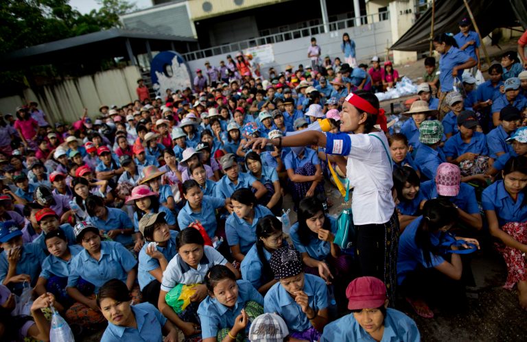 A labor leader uses a loudspeaker to address workers outside South Korean owned Master Sports Footwear factory that has been shut down without informing the workers four-weeks ago, outskirts of Yangon, Myanmar, Thursday, July 17, 2014. About 700 workers who lost their jobs as the Korean owner shut the factory, marched to the South Korean embassy in Yangon shouting slogans, demanding wages and compensation. (AP Photo/Gemunu Amarasinghe)