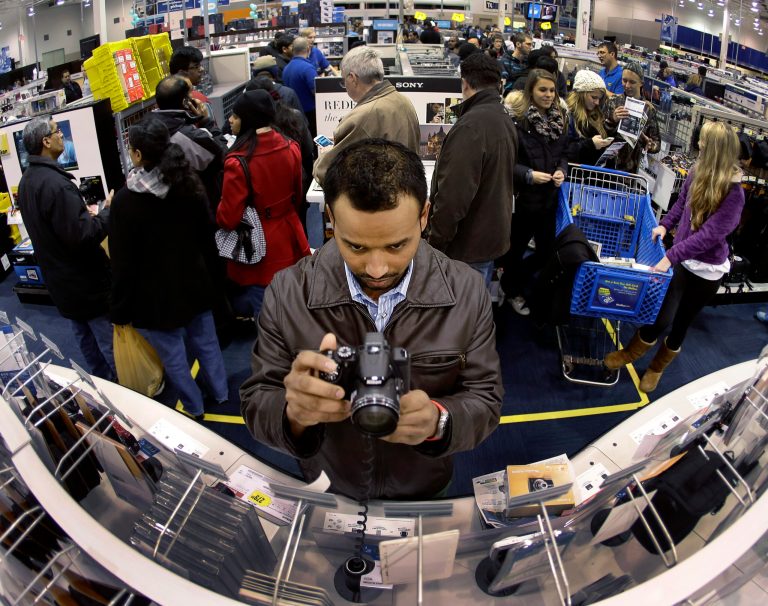 FILE - In this Nov. 28, 2013 file photo, Ripan Bhowmik looks at cameras while shopping at Best Buy in Overland Park, Kan. Americans are expected to spend at the highest rate in three years during what's traditionally the busiest shopping season of the year, the National Retail Federation said Tuesday, Oct. 7, 2014. (AP Photo/Charlie Riedel, File)