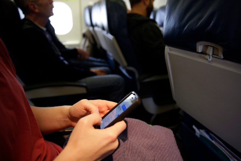 A passenger check her cell phone before a flight, Thursday, Oct. 31, 2013, in Boston. The Federal Aviation Administration issued new guidelines Thursday, Oct. 31, 2013, under which passengers will be able to use devices to read, work, play games, watch movies and listen to music, from the time they board to the time they leave the plane. (AP Photo/Matt Slocum)