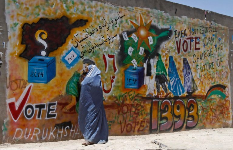 An Afghan woman walks past a mural to support voting in Kandahar, south of Kabul, Afghanistan, Friday, June 13, 2014. With fears of violence high, Afghanistan braced for a final election on Saturday to choose a new president to replace the only leader the nation has known since the Taliban were ousted and guide the transition to a country that will have to wean itself off near-total dependence on international aid after foreign combat troops withdraw at the end of this year. (AP Photo/Allauddin Khan)