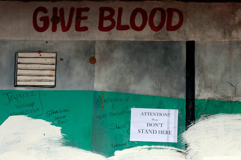 A sign asking for people not to stand is plastered on a wall across from  the Island Clinic Ebola isolation and treatment center in Monrovia, Liberia, Friday Sept. 26, 2014.  The outbreak of Ebola has overwhelmed the weak health systems of some of the world's poorest countries - there aren't enough doctors and nurses or even clinics to treat the spiraling number of cases.(AP Photo/Jerome Delay)