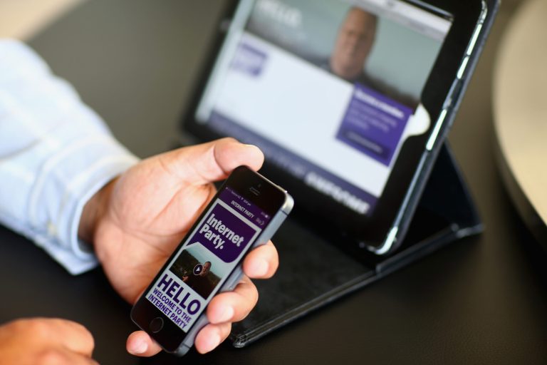Internet Party CEO Vikram Kumar shows the sign up app on his smartphone after the Internet Party was launched by Kim Dotcom at the Dotcom Mansion on March 27, 2014 in Auckland, New Zealand. The Internet Party today launched its membership drive with members paying $1.29 to join up. (Photo by Phil Walter/Getty Images)