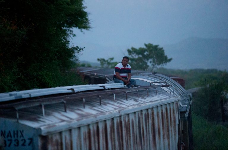 In this Aug. 26, 2014 photo, a Central American migrant sits alone atop a freight train as it heads north from Arriaga to Ixtepec, Mexico. A Mexican crackdown seems to be keeping women and children off the deadly train, known as 