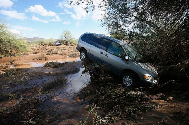 A vehicle sits atop debris where flash flood waters pushed it after rising waters overran Skunk Creek after strong storms moved through, Tuesday, Aug. 19, 2014, in New River, Ariz., just northwest of Phoenix. Heavy monsoon season rains that swept across Arizona on Tuesday led to dramatic rescues, road closures and flight delays as a series of fast-moving storms pummeled the state.  (AP Photo/Ross D. Franklin)