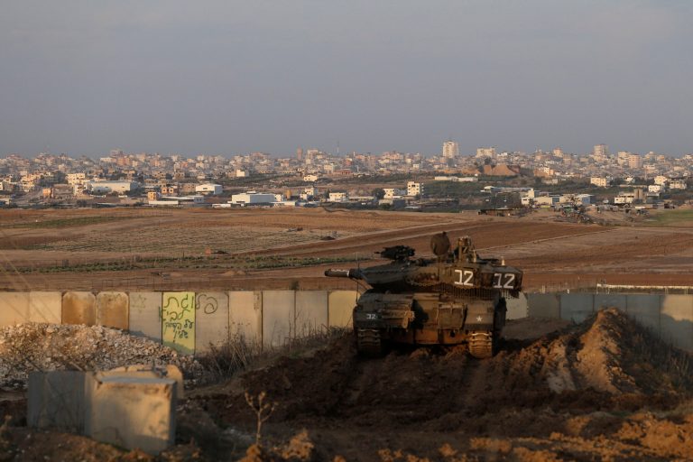 An Israeli tank is parked in a position overlooking the Gaza Strip, seen in the background at the Israel and Gaza border, on Dec. 25. (AP Photo/Tsafrir Abayov)