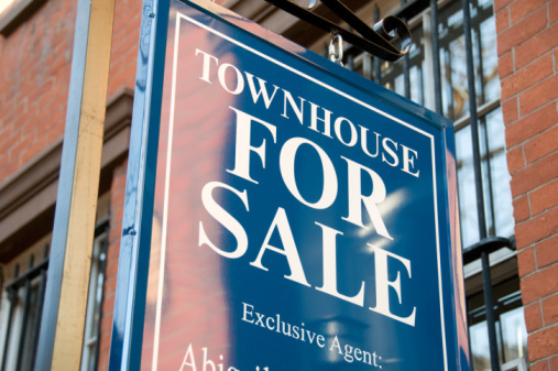 For sale sign on exterior of brick building