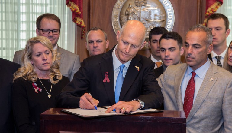 Florida Gov. Rick Scott signs the Marjory Stoneman Douglas Public Safety Act in the governor's office at the Florida State Capitol in Tallahassee, Fla., on Friday. (AP Photo/Mark Wallheiser)
