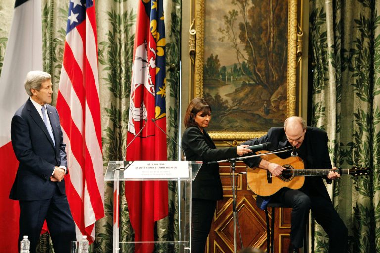 U.S. Secretary of State John Kerry, left, and Paris' Mayor Anne Hidalgo, center, listen to singer James Taylor as he performs during a ceremony, at the Paris city hall. (AP Photo/Thibault Camus)