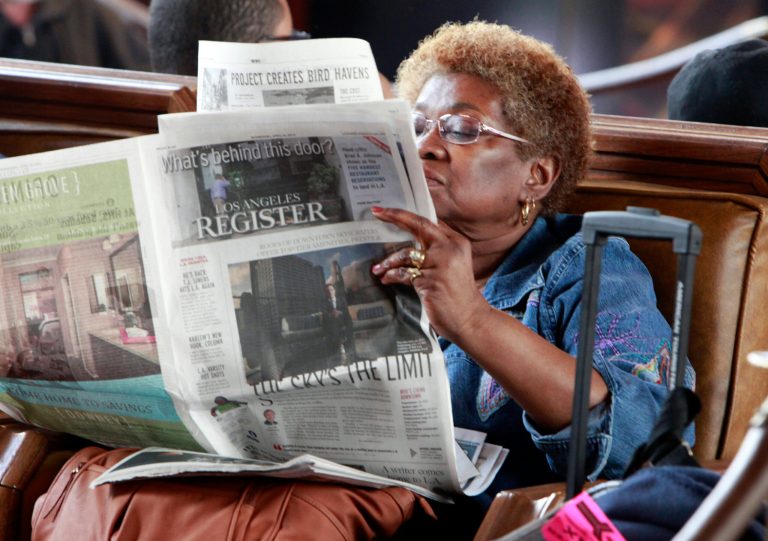 FILE - In this April 16, 2014 file photo, Dorothy Shumrt reads the Los Angeles Register newspaper on the day of it's launch while waiting for a train at Union Station, in Los Angeles. The Los Angeles Register, which debuted in April as a challenger to the Los Angeles Times, has ceased publication. Freedom co-owners Aaron Kushner and Eric Spitz sent a memo to employees Monday night, Sept. 22, 2014, announcing that the LA Register was closing. In announcing the closure, Freedom Communications Inc. also said it had sold the Santa Ana headquarters for its flagship paper, the Orange County Register, for $27 million to local developer Michael Harrah.
