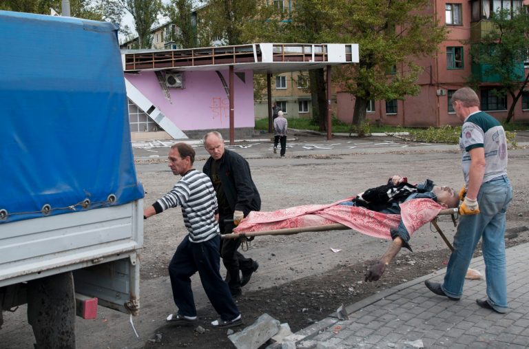 People carry a stretcher with a dead man after shelling by the Ukrainian forces in Makiivka, 25 km (16 miles) from Donetsk, eastern Ukraine, Tuesday, Aug. 19, 2014.  Government troops on Tuesday pressed attacks in the two largest cities held by pro-Russian rebels in eastern Ukraine, as Kiev also pursued diplomatic efforts to resolve the conflict that has killed more than 2,000. (AP Photo/Antoine E.R. Delaunay)